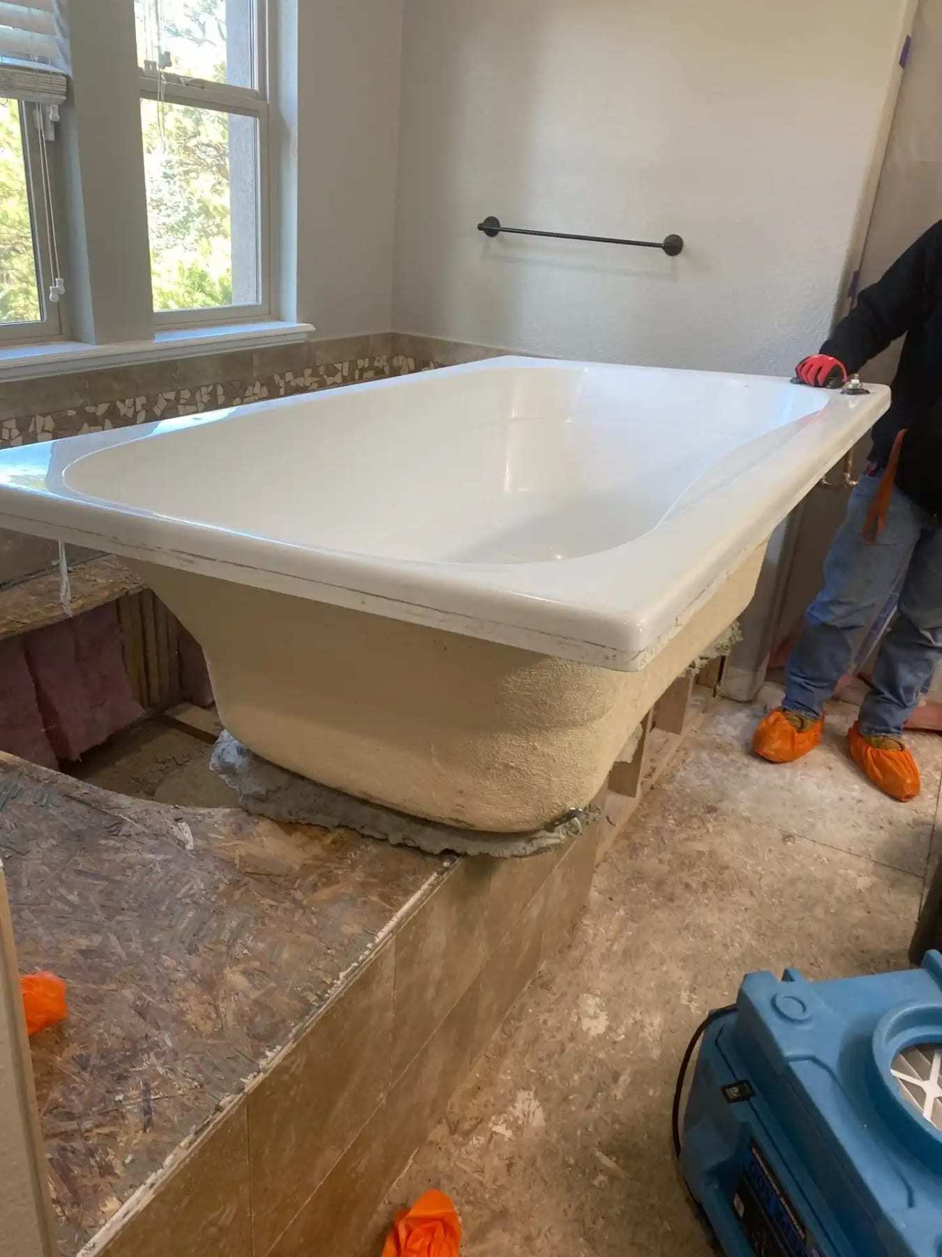 Bathtub with its surround removed and an air mover drying the subfloor