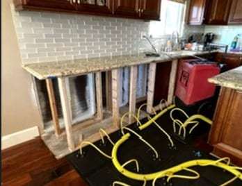 Kitchen cabinet base opened with drying hoses and a dehumidifier