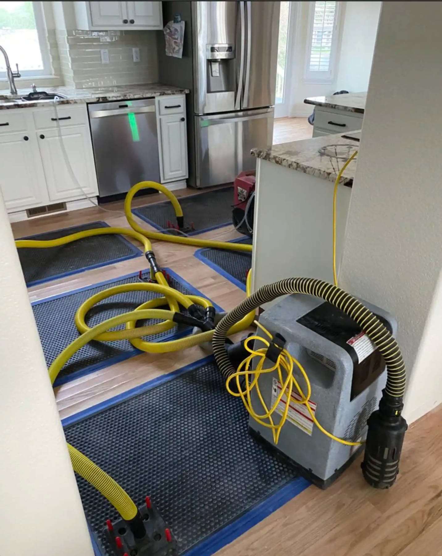 Kitchen floor with drying mats and hoses in front of the cabinets